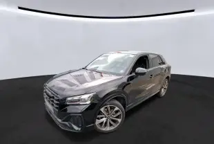 Audi Q2 noir vue 3/4 avant droit en intérieur, avec jantes alu et calandre S-Line distinctive.