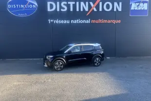Vue latérale droite d'une Citroën C3 Hybride 145 e-DSC6 MAX noire avec toit blanc, stationnée devant un mur noir.