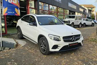 Mercedes GLC 220 Coupé blanc en 3/4 avant droit, avec calandre diamant et jantes alliage foncé, stationné devant un garage.