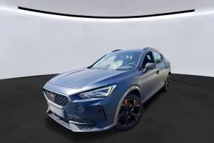 Vue 3/4 avant d'une CUPRA Formentor bleu mat avec jantes noires, dans un showroom au sol gris et mur bois.
