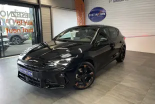 Vue 3/4 avant droite d'une CUPRA Leon noire avec jantes alliage cuivrées dans un showroom intérieur.