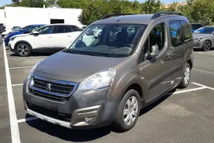 Peugeot Partner Tepee marron vue 3/4 avant droit, avec barres de toit et pare-chocs avant noir mat, stationné en extérieur.