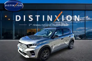 Vue 3/4 avant d'une Citroën C3 gris mercure garée devant une vitrine avec logo Distinxion.