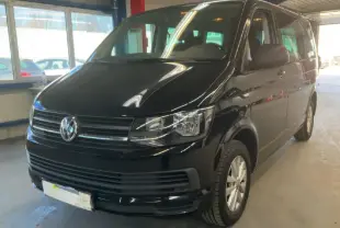 Volkswagen Multivan T6 noir vu en 3/4 avant droit dans un garage avec éclairage intérieur chaud.
