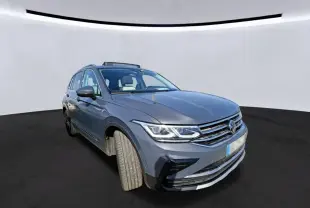 Volkswagen Tiguan gris 3/4 avant droit avec toit ouvrant panoramique visible sur fond neutre.