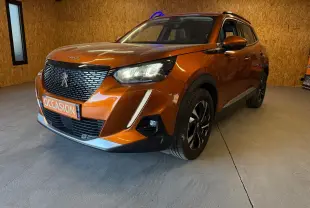 Peugeot 2008 orange vue 3/4 avant droit avec calandre noire et feux LED allumés en intérieur.