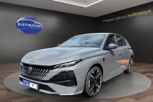 Peugeot 308 gris clair vue 3/4 avant avec calandre distinctive et jantes noires en showroom.