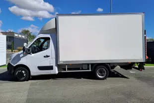 Vue de profil côté gauche d’un Nissan Interstar châssis cabine blanc 2024 avec caisse de livraison sur fond urbain.