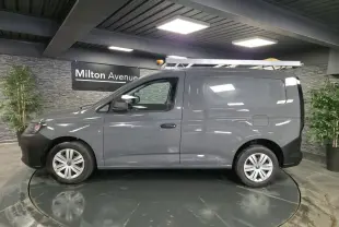 Vue latérale droite d’un Volkswagen Caddy Cargo gris 2022 avec galerie de toit et jantes acier noires.