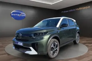 Vue 3/4 avant d'un Citroën C3 Aircross hybride vert avec toit blanc et jantes modernes en showroom.