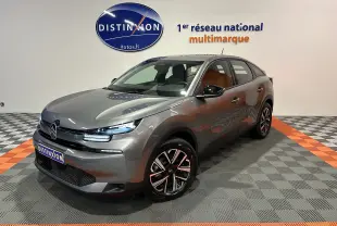 Citroën E-C4 électrique gris foncé en 3/4 avant droit, avec jantes noires et phares LED allumés en showroom.