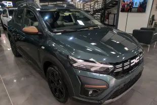 Dacia Sandero Stepway TCe 110 vert cèdre en 3/4 avant droit, avec rétroviseurs bronze et jantes noires en showroom.