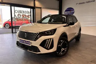 Peugeot 2008 blanc vue 3/4 avant droit en intérieur, avec calandre verticale et jantes noires distinctives.