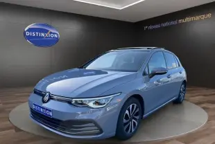 Volkswagen Golf VIII gris lunaire vue 3/4 avant en intérieur avec jantes alu et toit panoramique visible.