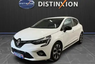 Renault Clio V blanche vue 3/4 avant droit, jantes bi-ton et rétroviseurs noirs, stationnée en intérieur showroom.