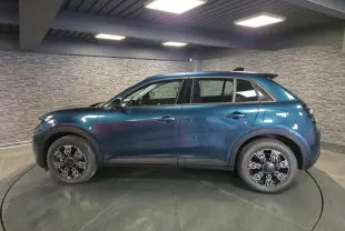 Vue de profil côté gauche d'un FIAT 600 1.2 Hybrid bleu métallisé avec jantes alliage et toit noir en intérieur showroom.