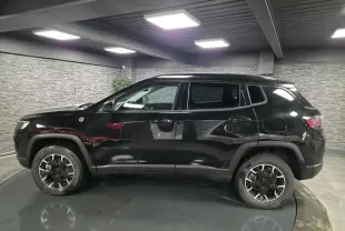 Jeep Compass Trailhawk noir en profil côté gauche, avec jantes alliage 17'' et vitres surteintées dans un garage.