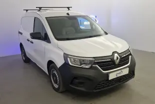 Renault Kangoo blanc en 3/4 avant droit, utilitaire avec calandre noire et barres de toit visibles.