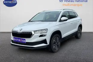 SUV Skoda Karoq blanc glacier vu en 3/4 avant droit, avec calandre noire et jantes bi-ton.
