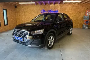 Audi Q2 noir vue 3/4 avant droit dans un showroom avec calandre chromée et jantes argentées.