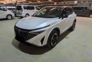 Vue 3/4 avant droit d'un Nissan Qashqai blanc nacré avec toit noir et jantes alliage dans un parking intérieur.