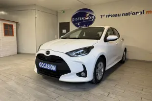Vue 3/4 avant droite d'une Mazda2 blanche 2023 hybride en showroom avec plaque "OCCASION" visible.