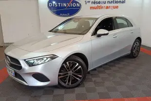Mercedes Classe A 250 e Business Line gris clair vue 3/4 avant droit en intérieur showroom avec jantes noires et chromées.