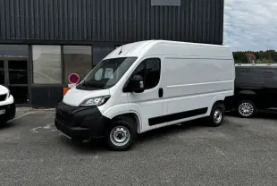 Vue 3/4 avant droite d’un Peugeot Boxer Fourgon blanc avec pare-chocs noir et jantes acier, stationné devant un bâtiment.