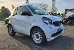 Vue 3/4 avant droite d'une Smart Fortwo Coupé électrique blanche de 2019 avec jantes acier et traces d'usure sur le pare-chocs.