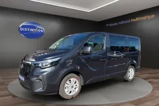 Vue 3/4 avant droit d'un Nissan Primastar gris foncé avec portes latérales, présenté en showroom.