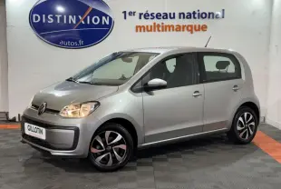 Volkswagen Up gris clair vue de profil côté droit, feux allumés, jantes noires et argentées en intérieur showroom.