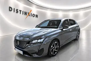 Peugeot 308 gris 3/4 avant droit, avec calandre distinctive et jantes alliage modernes.