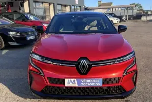Vue frontale d'une Renault Mégane E-Tech Electric rouge flamme 2023 avec logo noir et plaque "Véhicules Occasions" visible.