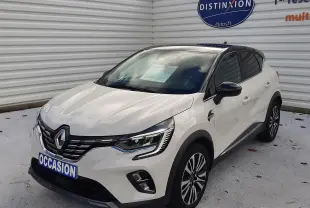 Renault Captur blanc avec toit noir vu de 3/4 avant droit, mettant en valeur ses optiques LED et sa calandre distinctive.