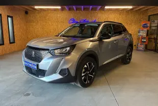 Peugeot 2008 gris métallisé vue 3/4 avant droit dans un showroom avec jantes noires et toit noir.