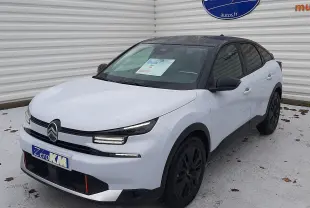 Vue 3/4 avant d'une Citroën C4 hybride blanche Okenite avec toit noir Perla et jantes noires, stationnée devant un mur blanc.