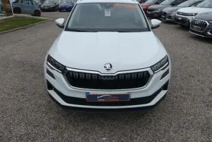 Vue avant d'un SUV Skoda Karoq blanc 2024 avec calandre noire et phares LED, en extérieur sur parking.