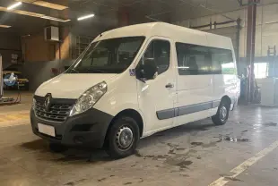 Renault Master blanc vu en 3/4 avant droit dans un garage, avec logo handicap sur la porte côté conducteur.