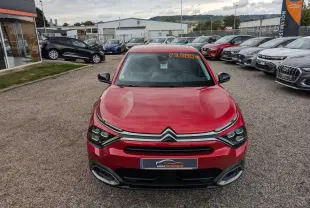 Vue avant d'une Citroën C4 rouge foncé 2024 avec calandre chromée et prix affiché sur pare-brise