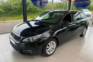 Peugeot 308 SW noir perla nera vue 3/4 avant droit, jantes alu et barres de toit visibles en showroom.
