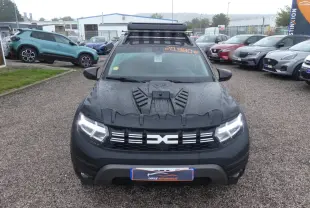 Vue avant d'un Dacia Duster noir 2023 avec covering intégral et galerie de toit sur un parking humide.