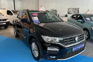 Volkswagen T-Roc noir métal vue 3/4 avant droit en showroom avec étiquette promotionnelle sur le pare-brise