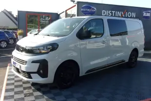 Vue 3/4 avant droite d'un Opel Vivaro XL blanc 2025 avec jantes noires et vitres teintées, stationné en extérieur.