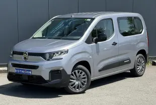Citroën Berlingo ë-136 gris Artense en 3/4 avant droit, avec jantes tôles et protections latérales noires.