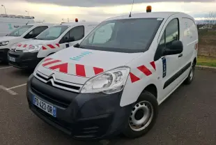 Vue 3/4 avant droit d'un Citroën Berlingo blanc utilitaire avec bandes rouges diagonales et gyrophare orange sur le toit.