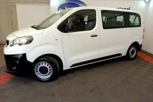 Vue de profil côté gauche d’un Peugeot Traveller blanc 2018 avec jantes acier et pare-chocs noirs, en intérieur.