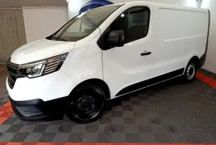 Fourgon blanc Renault Trafic FG CF L1H1 vu de profil côté gauche dans un espace fermé avec sol à motifs noirs et rouges.