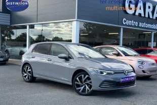 Volkswagen Golf 1.5 TSI gris lunaire en 3/4 avant droit, avec jantes alliage et phares LED allumés.