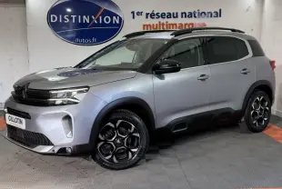 Citroën C5 Aircross gris clair en 3/4 avant droit, avec jantes noires et toit noir contrasté en intérieur showroom.