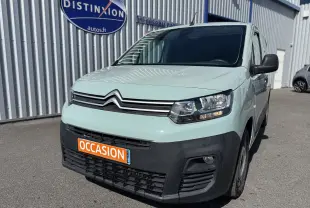 Vue 3/4 avant droit d’un Citroën Berlingo beige 2019 avec pare-chocs noir et plaque orange « OCCASION » devant un bâtiment industriel.